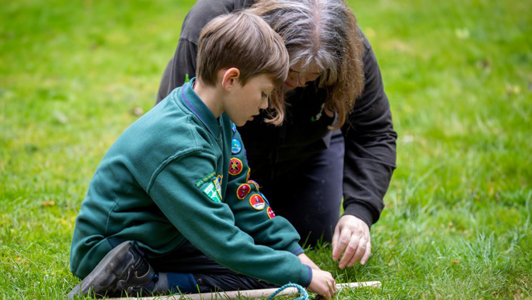 Cubs leader helping child tie a rope