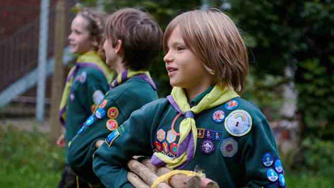 Children dressed in Cubs uniforms carrying sticks