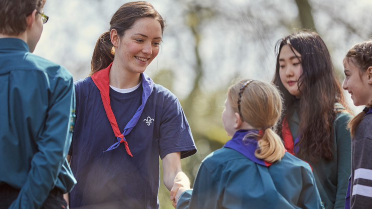 A girl scout shaking another scout's hand