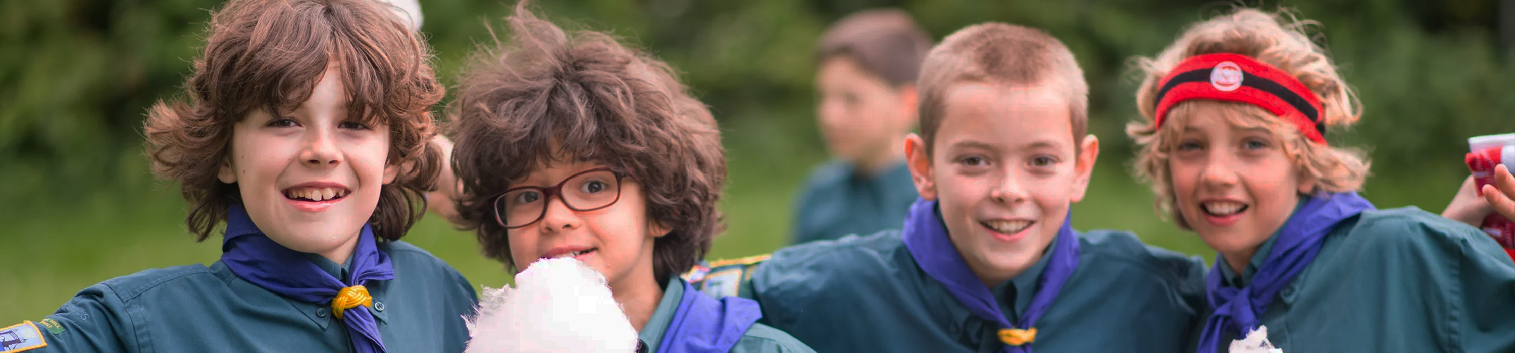 Young people dressed in Scouts uniforms smiling at the camera