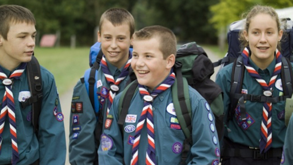 Young people dressed in Scouts uniforms smiling